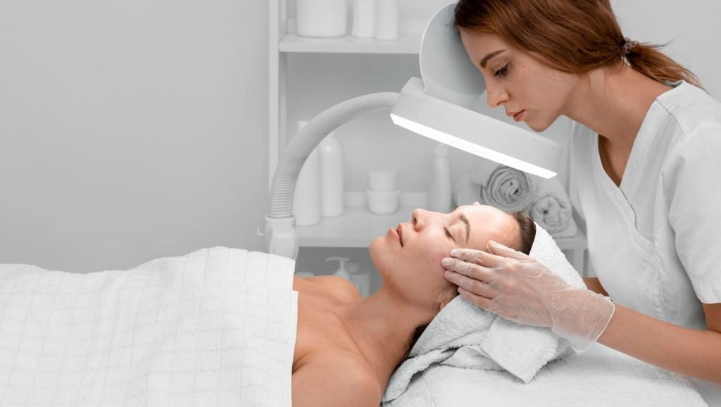 Mujer haciendo tratamiento facial a otra mujer en clínica estética